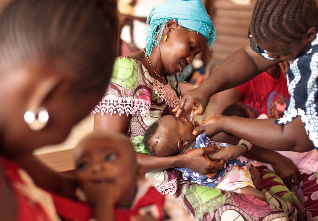 BOOST-Mother-holding-child-receiving-oral-polio-vaccine