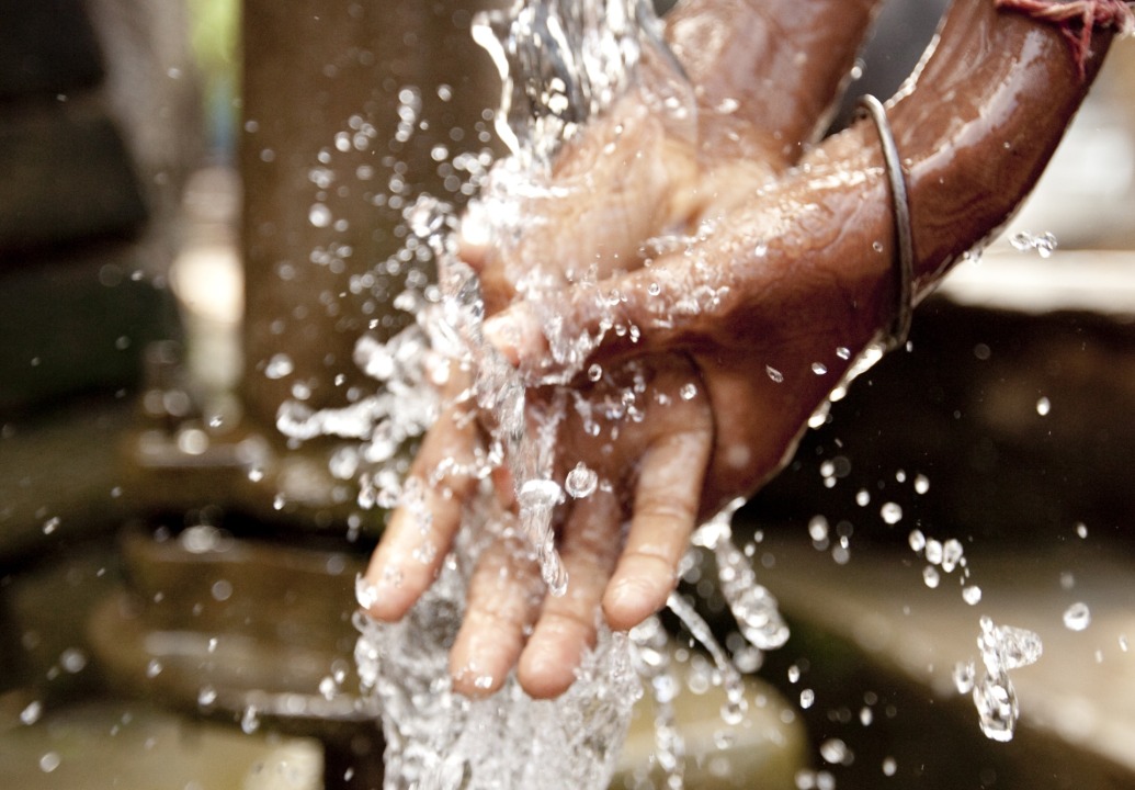 child-washes-hand-in-well-water