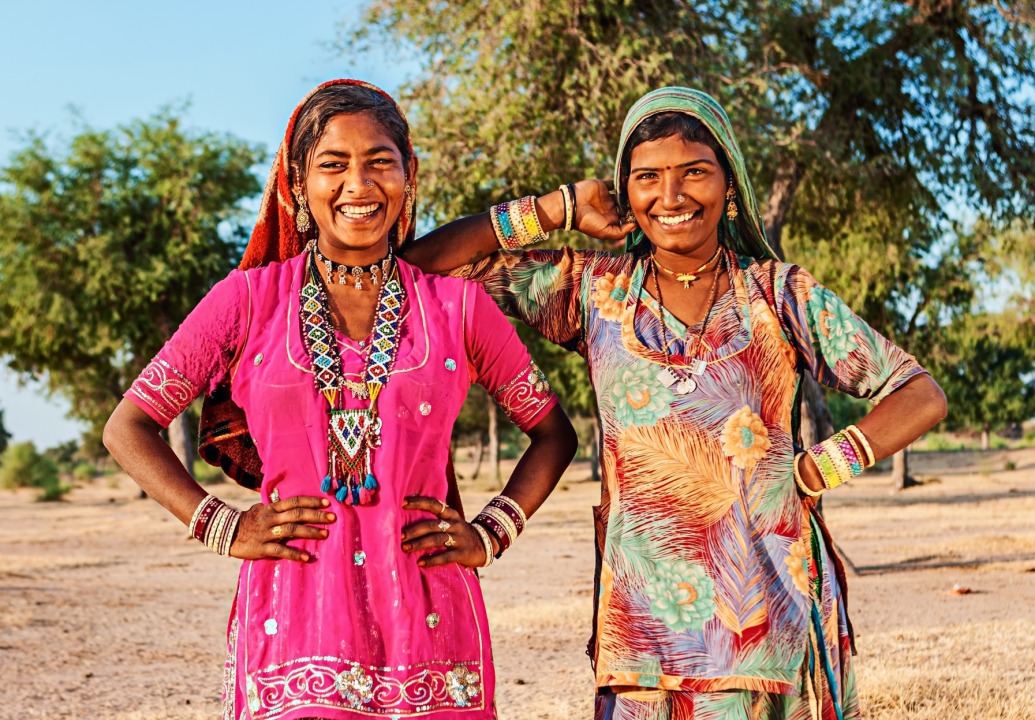 Two Indian women smiling at the camera with colorful dresses