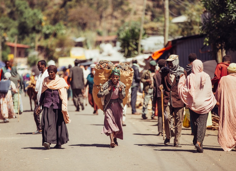 Woman walking down the street carrying a heavy load.