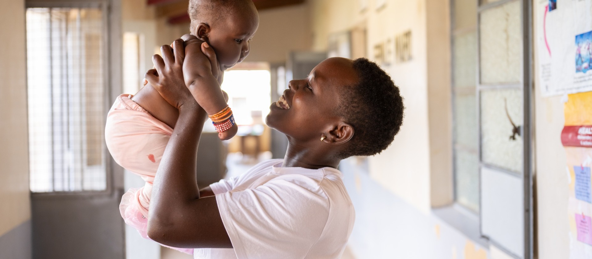 Woman is holding her baby and they are smiling at each other.